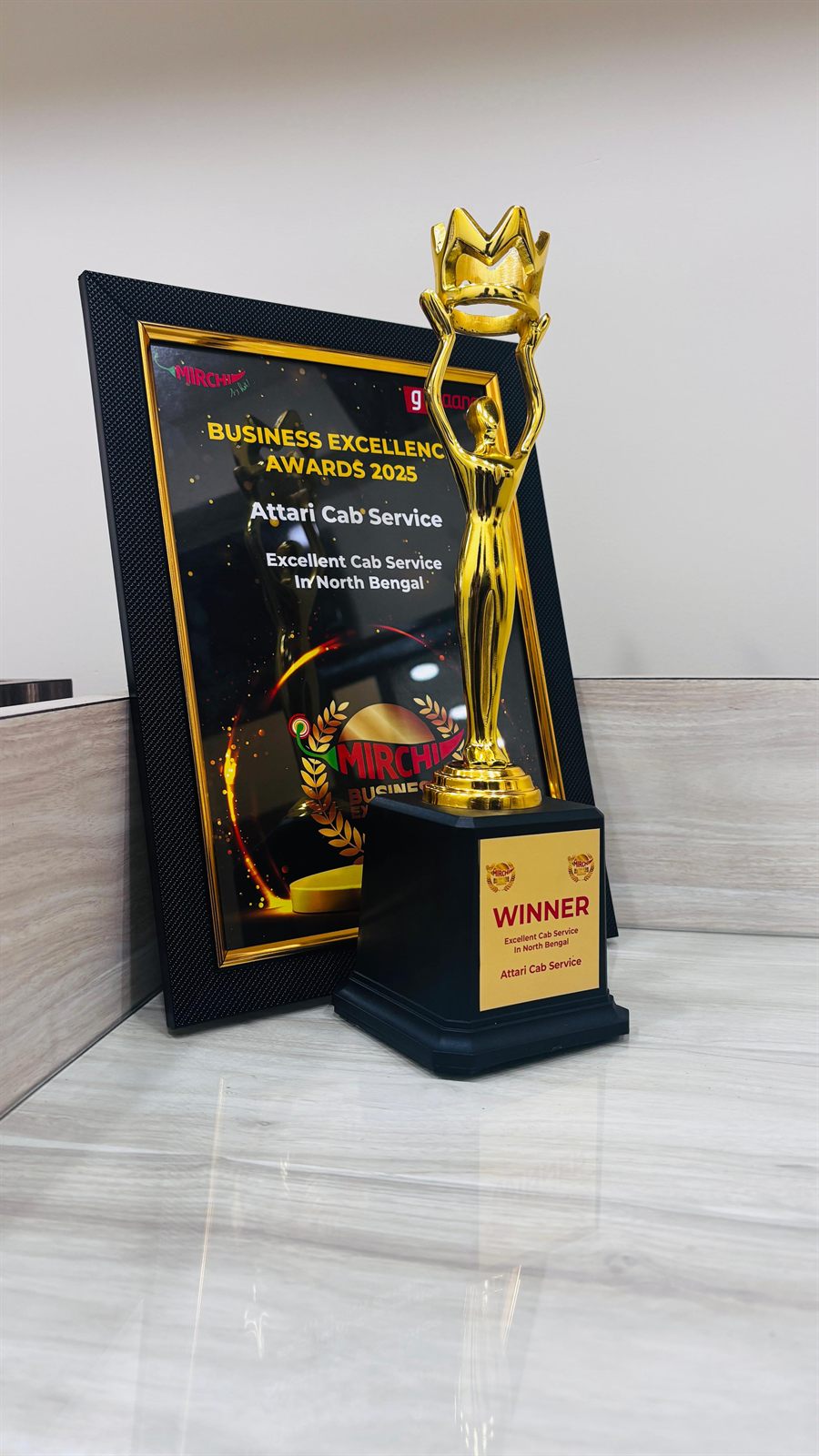 Mirchi Business Excellence Awards 2025 winner's trophy for Excellent Cab Service in North Bengal, in front of the framed citation