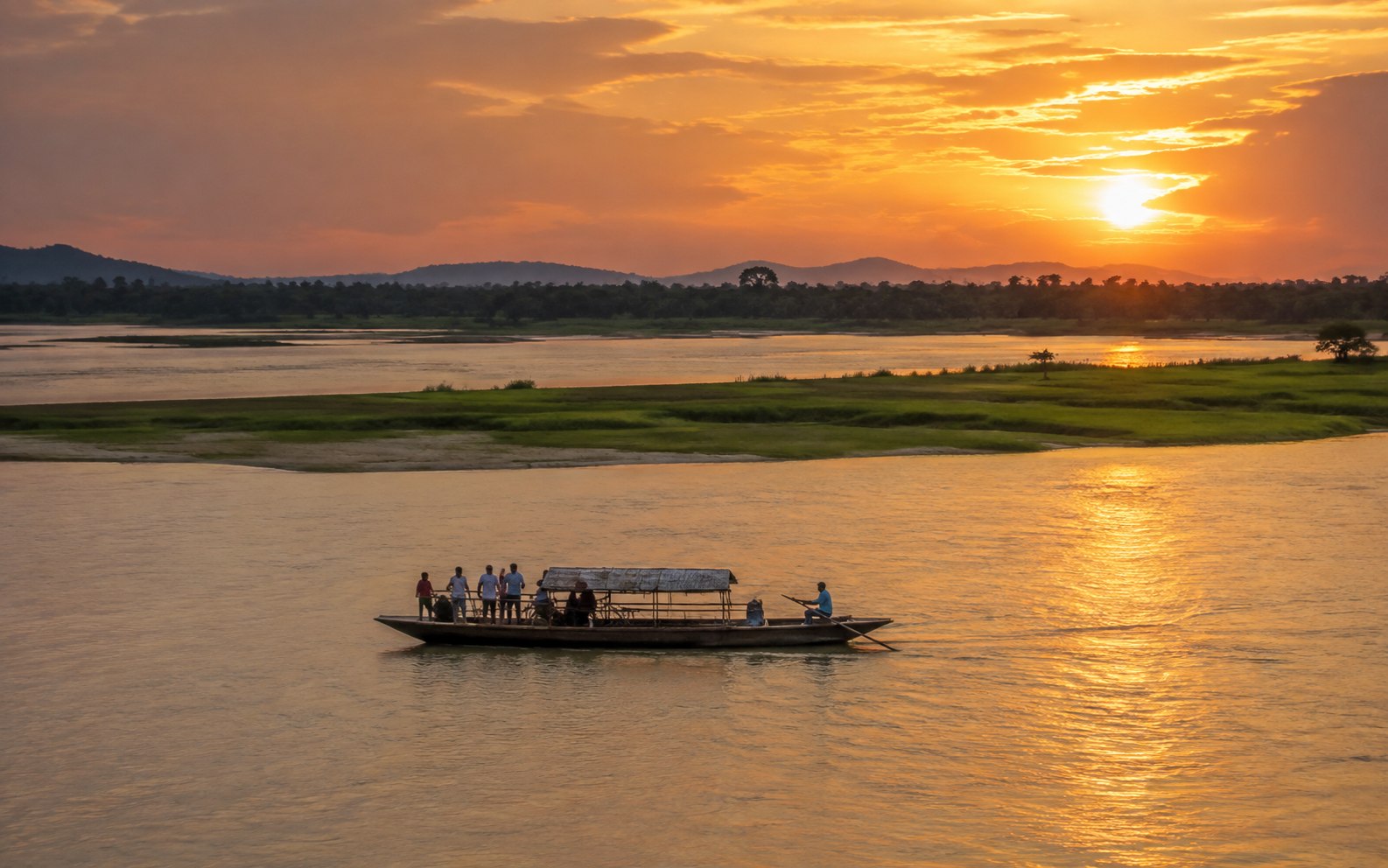 Boat crossing the Brahmaputra River at sunset in Assam